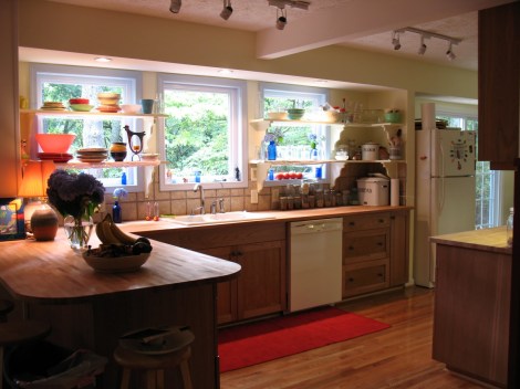 Custom built kitchen cabinetry services. Cherry Mission-Style cabinets with butcher block counter tops.  These counter tops have a beautiful tumbled marble tile back splash. The 3 windows were installed which created a perfect space for some open shelving. 